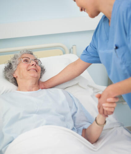 Patient smiling to a nurse while holding her hand